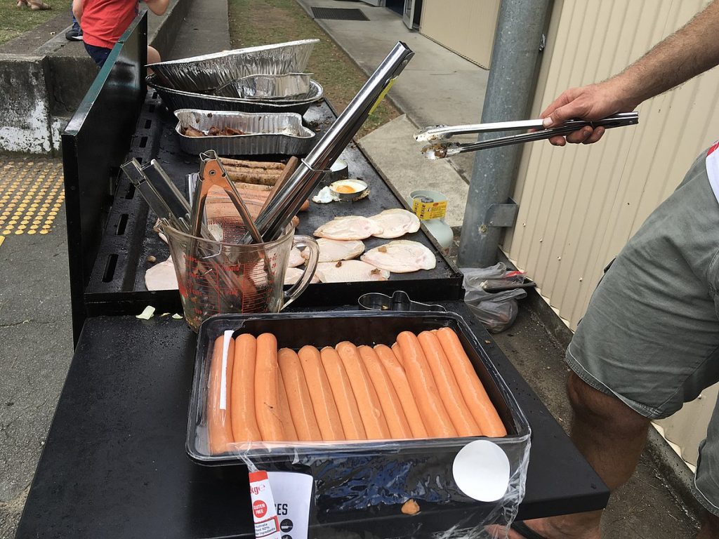 A man cooking hot dogs on a grill