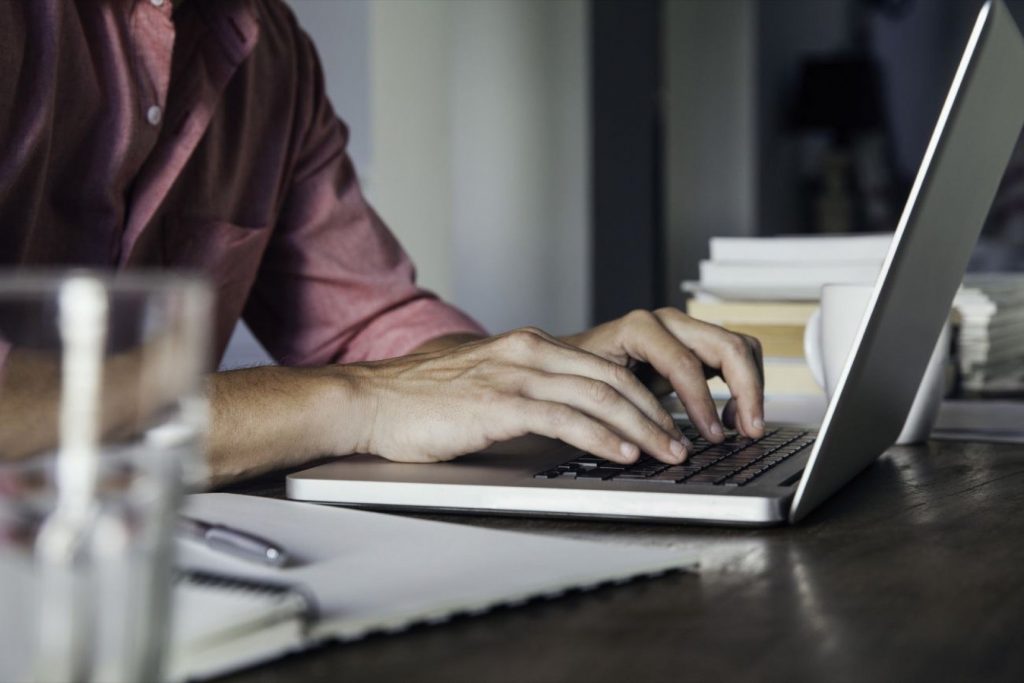 A man sitting at a table using a laptop computer